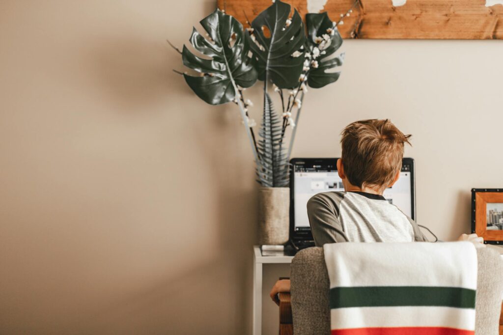 Young boy studying at home on a laptop for online learning in a cozy room.